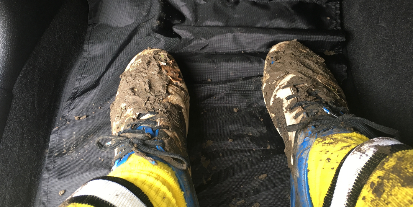 Muddy football boots in seat well in car